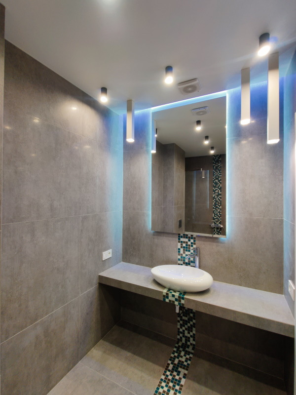 На фото: главная, серо-белая ванная комната среднего размера в современном стиле с плоскими фасадами, серыми фасадами, полновстраиваемой ванной, душем над ванной, инсталляцией, серой плиткой, керамической плиткой, серыми стенами, полом из керамической плитки, накладной раковиной, столешницей из плитки, серым полом, открытым душем, серой столешницей, зеркалом с подсветкой, тумбой под одну раковину и подвесной тумбой