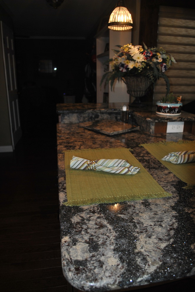 Kitchen - brown floor kitchen idea with brown cabinets, beige backsplash, stainless steel appliances, an island and gray countertops