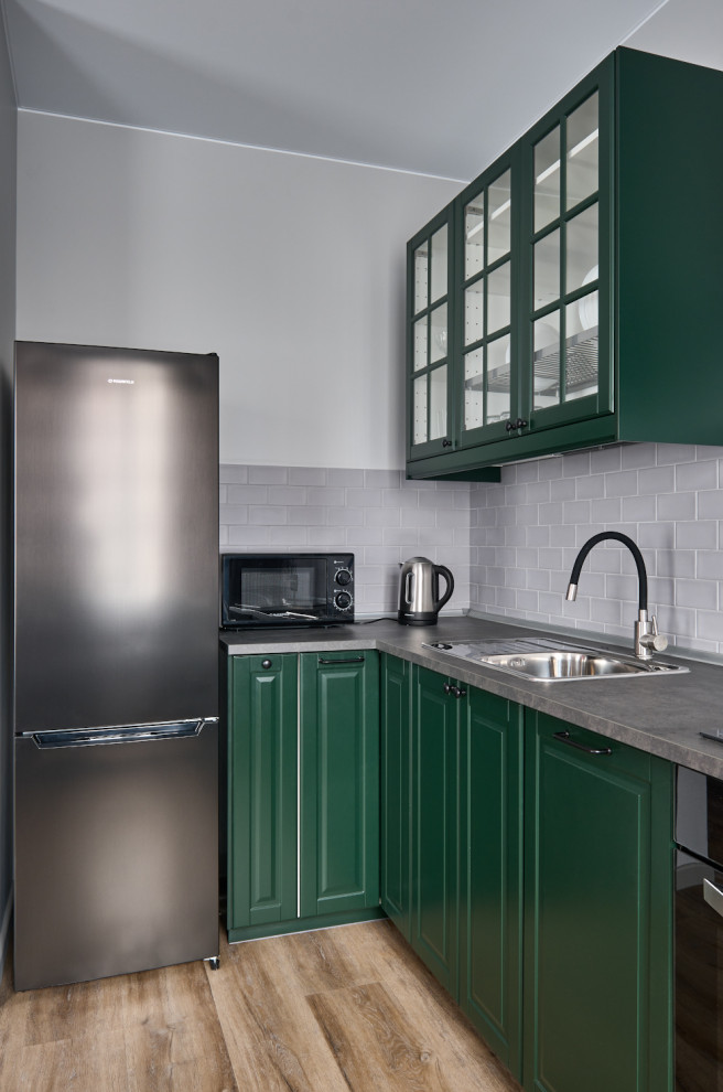 Idéer för ett mellanstort klassiskt grå kök, med en nedsänkt diskho, luckor med infälld panel, gröna skåp, laminatbänkskiva, grått stänkskydd, stänkskydd i keramik, svarta vitvaror, vinylgolv och brunt golv