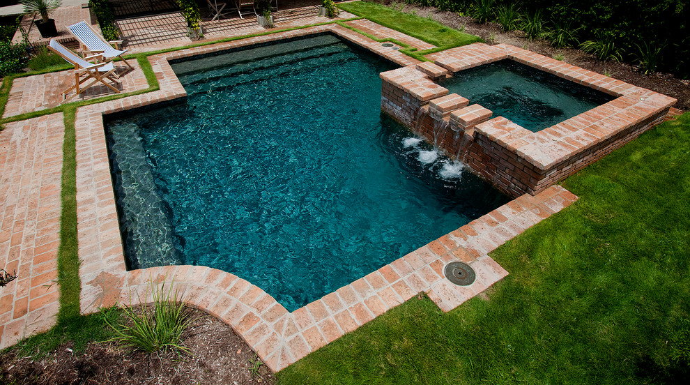 Inspiration for a small traditional backyard custom-shaped lap pool in Austin with brick pavers and a hot tub.