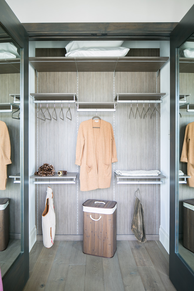 Photo of a mid-sized industrial women's built-in wardrobe in Denver with grey cabinets, light hardwood floors and grey floor.