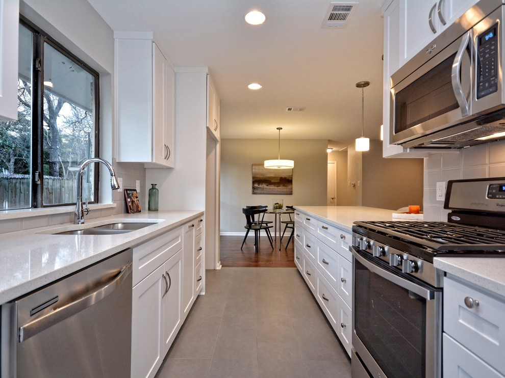 Inspiration for a mid-sized transitional galley porcelain tile open concept kitchen remodel in Austin with an undermount sink, shaker cabinets, white cabinets, quartzite countertops, gray backsplash, glass tile backsplash and stainless steel appliances
