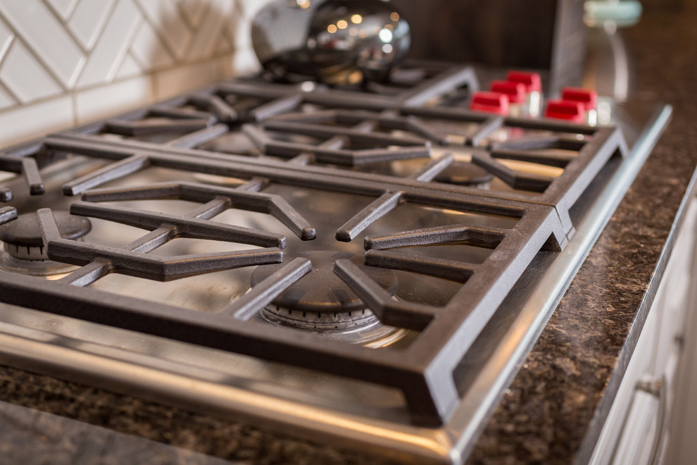 Large transitional l-shaped gray floor open concept kitchen photo with shaker cabinets, medium tone wood cabinets, granite countertops, white backsplash, subway tile backsplash, stainless steel appliances and an island
