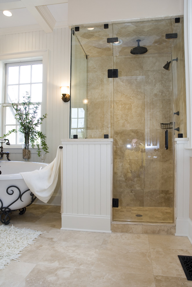 Large mediterranean master bathroom in Huntington with a claw-foot tub, a corner shower, beige tile, stone tile, white walls, limestone floors, granite benchtops, raised-panel cabinets, dark wood cabinets, a two-piece toilet, an undermount sink, beige floor and a hinged shower door.