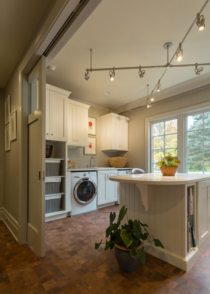 Design ideas for a large traditional utility room in Milwaukee with a drop-in sink, white cabinets, solid surface benchtops, grey walls, cork floors and a side-by-side washer and dryer.