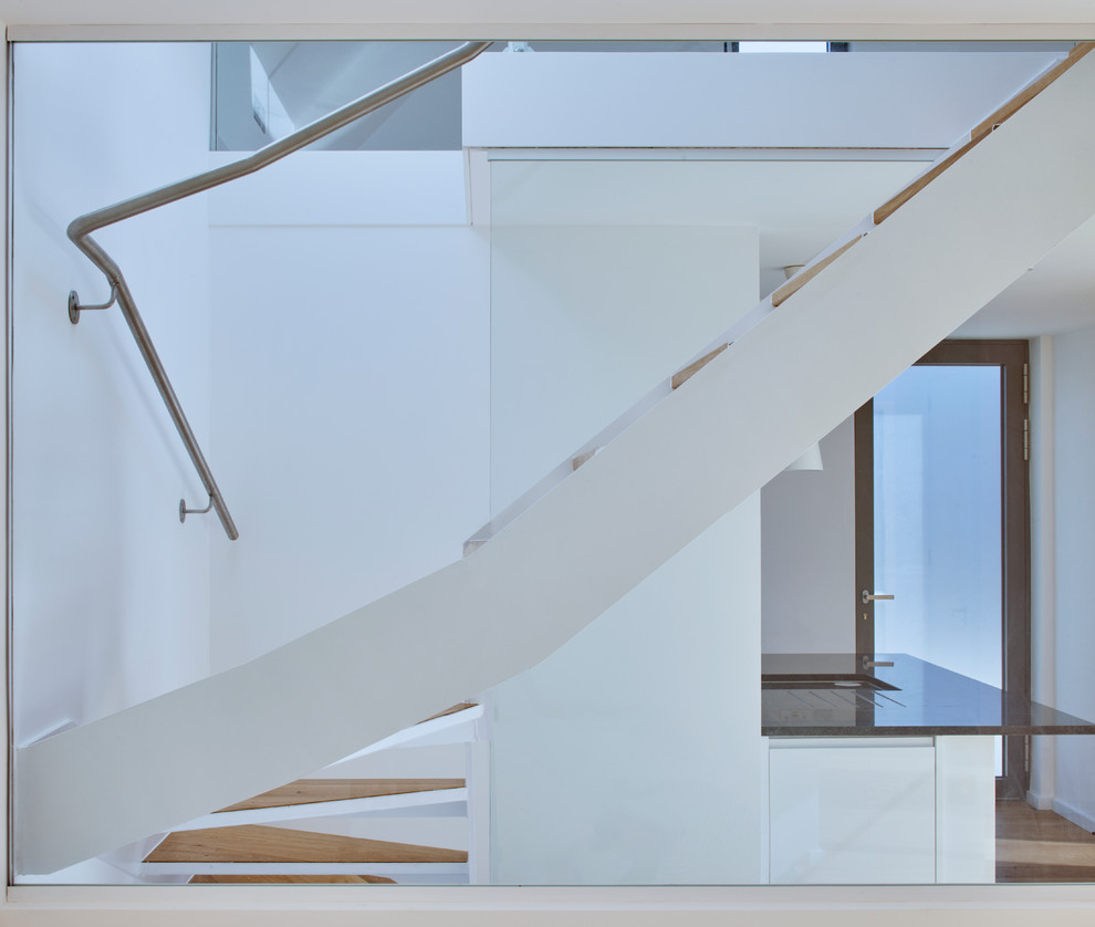 Small modern wood curved staircase in London with glass risers and glass railing.