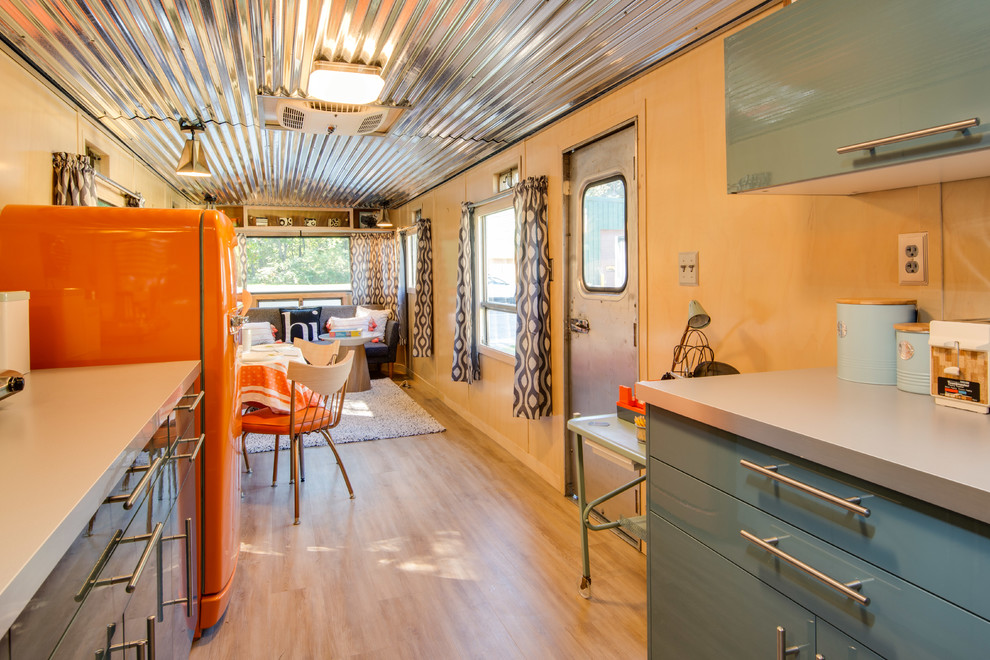 Small midcentury galley kitchen in Other with a single-bowl sink, flat-panel cabinets, blue cabinets, stainless steel benchtops, coloured appliances, no island, beige floor, vinyl floors and grey benchtop.