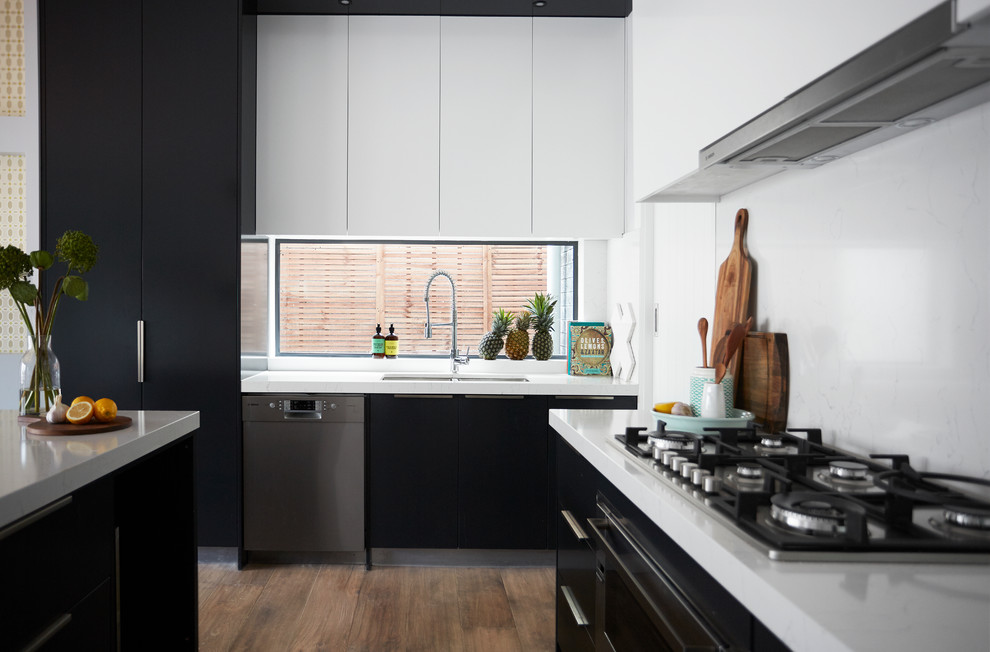 Large contemporary u-shaped eat-in kitchen in Melbourne with a double-bowl sink, flat-panel cabinets, black cabinets, white splashback, quartz benchtops, medium hardwood floors, marble splashback, stainless steel appliances, with island, brown floor and white benchtop.