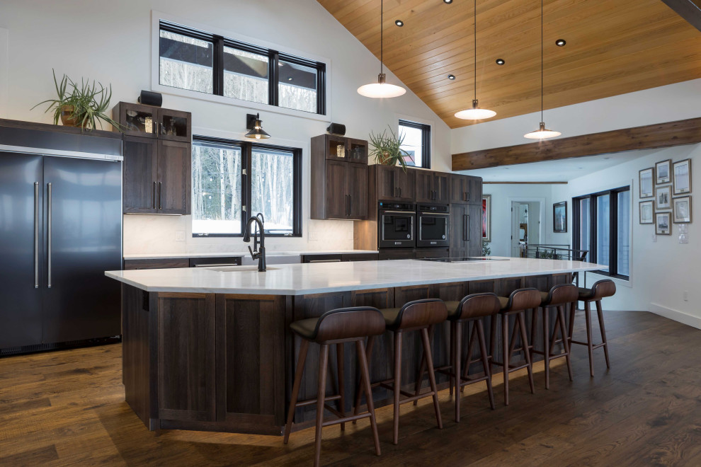 Example of a huge transitional single-wall dark wood floor, brown floor and shiplap ceiling open concept kitchen design in Denver with a farmhouse sink, shaker cabinets, dark wood cabinets, marble countertops, paneled appliances, an island and white countertops