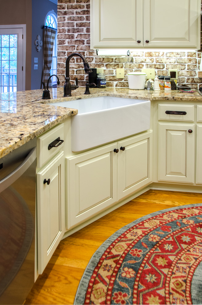 Eat-in kitchen - large transitional u-shaped medium tone wood floor eat-in kitchen idea in Raleigh with a farmhouse sink, raised-panel cabinets, beige cabinets, granite countertops, multicolored backsplash, terra-cotta backsplash, stainless steel appliances and a peninsula