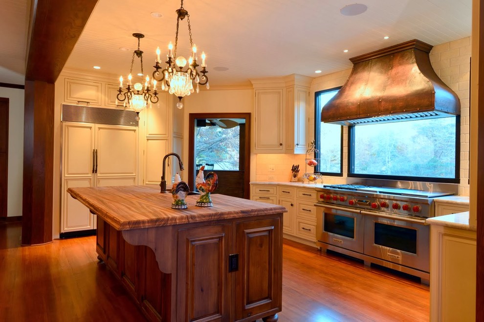 Eat-in kitchen - mid-sized rustic u-shaped medium tone wood floor eat-in kitchen idea with an undermount sink, raised-panel cabinets, white cabinets, marble countertops, white backsplash, brick backsplash, paneled appliances and an island