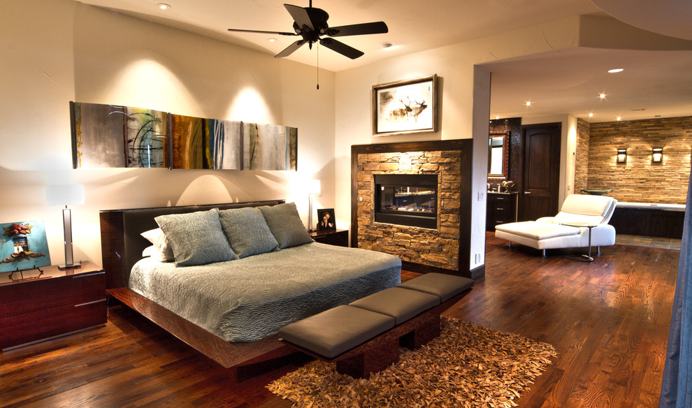 Design ideas for a large contemporary master bedroom in Dallas with beige walls, medium hardwood floors, a two-sided fireplace and a stone fireplace surround.