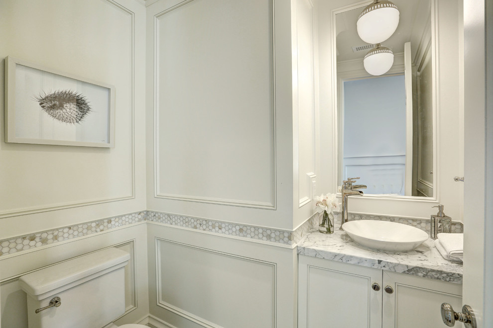 Small beach style powder room in Los Angeles with recessed-panel cabinets, white cabinets, multi-coloured tile, marble, white walls, marble floors, a vessel sink, marble benchtops, white floor, grey benchtops and a two-piece toilet.