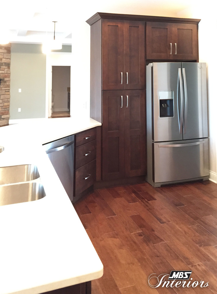 Inspiration for a large transitional medium tone wood floor and brown floor eat-in kitchen remodel with an undermount sink, shaker cabinets, stainless steel appliances, dark wood cabinets and a peninsula