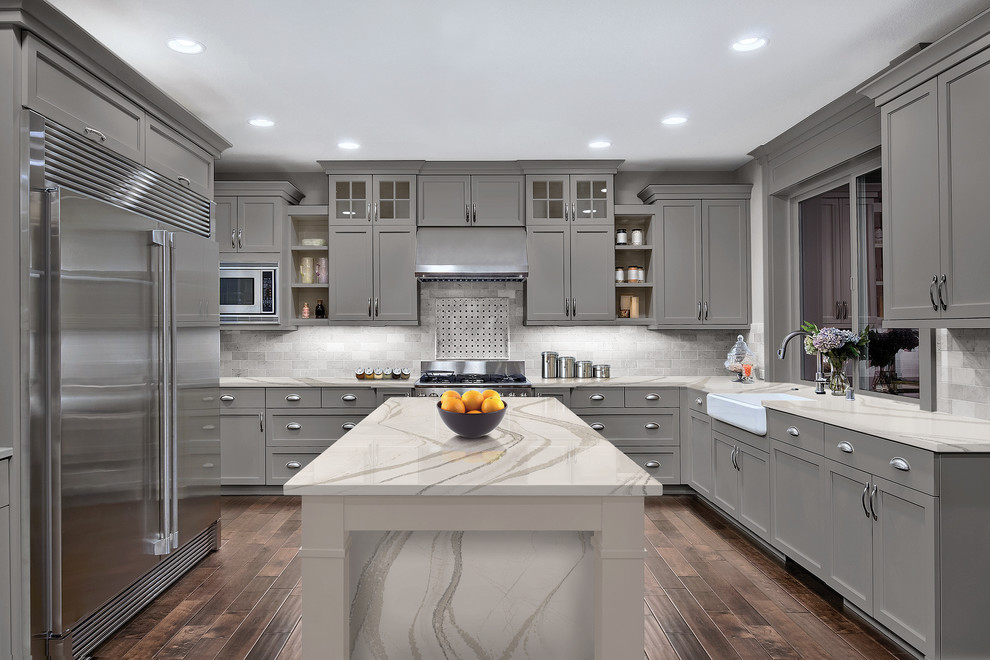 Design ideas for a transitional kitchen in Minneapolis with a farmhouse sink, shaker cabinets, grey cabinets, grey splashback, dark hardwood floors, with island and brown floor.