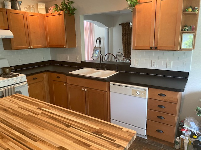 Example of a mid-sized u-shaped ceramic tile eat-in kitchen design with a double-bowl sink, shaker cabinets, brown cabinets, laminate countertops, yellow backsplash, subway tile backsplash, white appliances, an island and black countertops