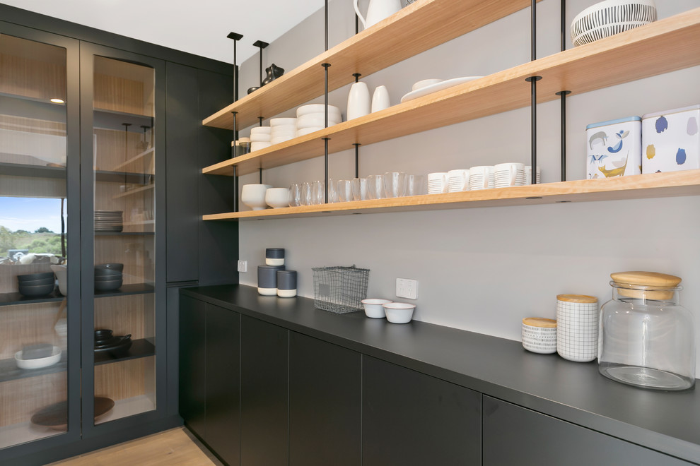Large modern u-shaped kitchen pantry in Wellington with raised-panel cabinets, grey cabinets, grey splashback, medium hardwood floors, brown floor and grey benchtop.