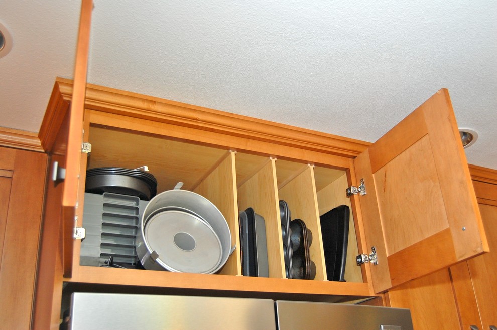Inspiration for a mid-sized transitional l-shaped laminate floor open concept kitchen remodel in Portland with an undermount sink, shaker cabinets, medium tone wood cabinets, quartz countertops, brown backsplash, glass tile backsplash, stainless steel appliances, a peninsula and multicolored countertops