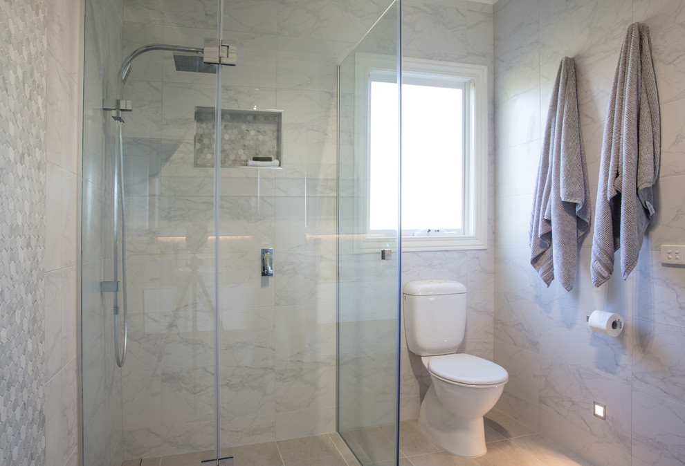 This is an example of a mid-sized contemporary master bathroom in Melbourne with white cabinets, a corner shower, a two-piece toilet, white tile, porcelain tile, white walls, porcelain floors, engineered quartz benchtops, grey floor and a hinged shower door.