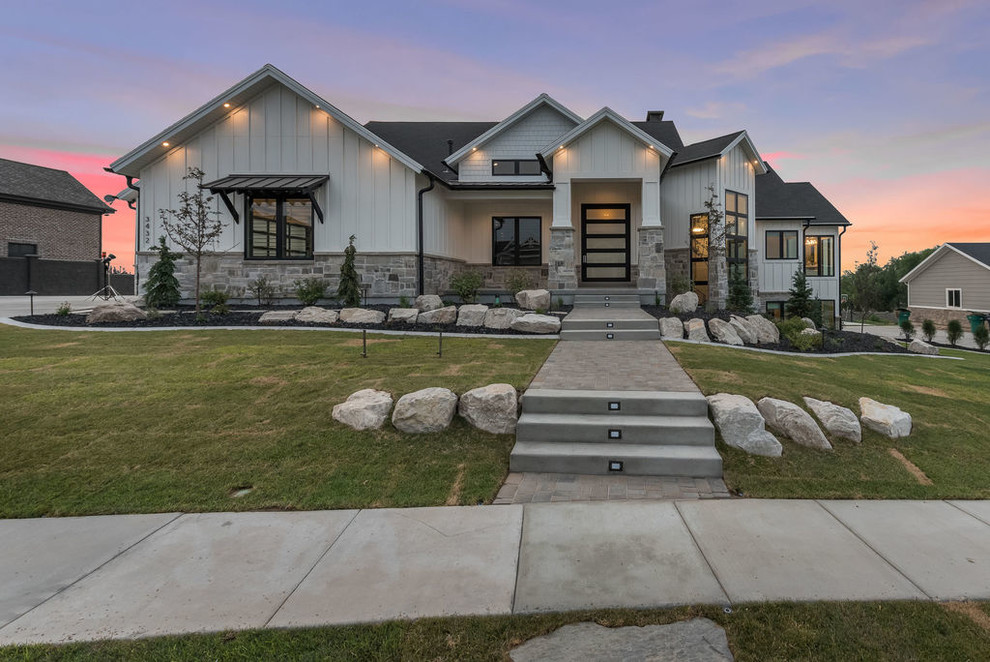 Photo of a large transitional one-storey black house exterior in Salt Lake City with stone veneer, a gable roof and a shingle roof.