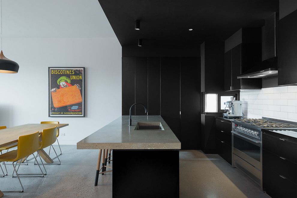 Photo of a small industrial u-shaped open plan kitchen in Melbourne with an integrated sink, flat-panel cabinets, black cabinets, concrete benchtops, white splashback, subway tile splashback, stainless steel appliances, concrete floors and a peninsula.