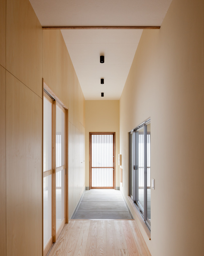 Immagine di un corridoio di medie dimensioni con pareti beige, parquet chiaro, una porta scorrevole, una porta marrone, soffitto in carta da parati e pareti in legno
