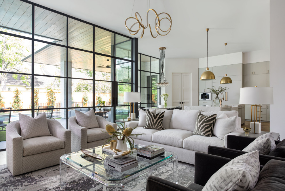 Inspiration for an expansive transitional open concept living room in Houston with white walls, light hardwood floors, a standard fireplace, a wall-mounted tv and brown floor.