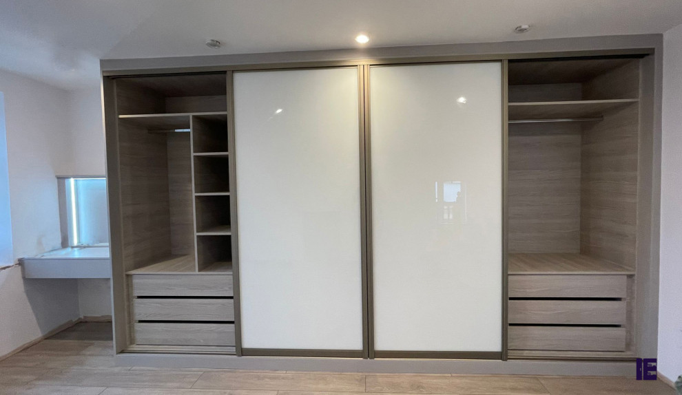 Small modern storage and wardrobe in London with white cabinets, plywood floors, brown floor and wood.