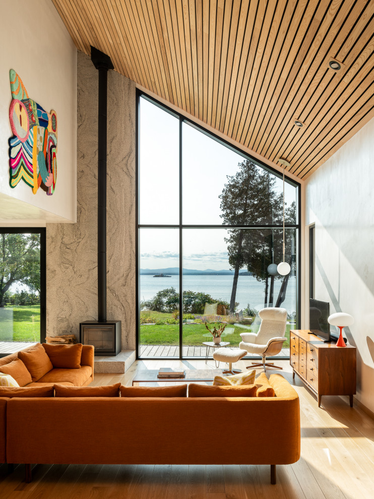 Inspiration pour un salon design ouvert avec un mur beige, parquet clair, un poêle à bois, un manteau de cheminée en pierre, un téléviseur indépendant et un plafond en bois.