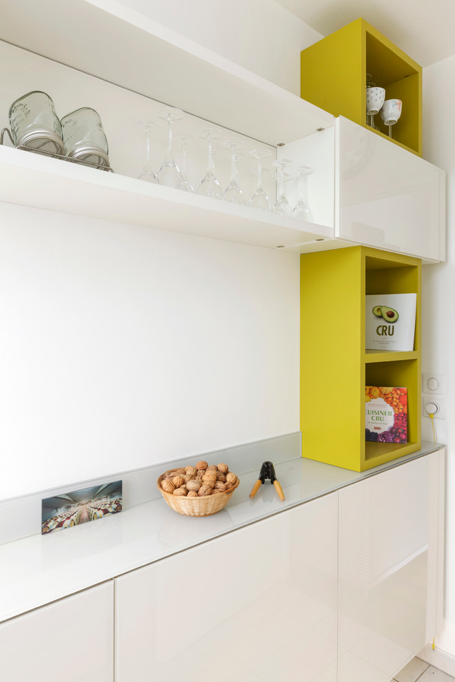 This is an example of a mid-sized contemporary separate kitchen in Paris with white cabinets and no island.