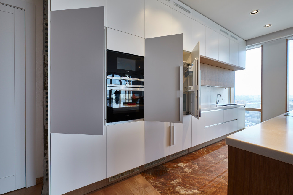 Inspiration for a large contemporary single-wall eat-in kitchen in Moscow with a double-bowl sink, white cabinets, white splashback, laminate floors, with island, brown floor and white benchtop.
