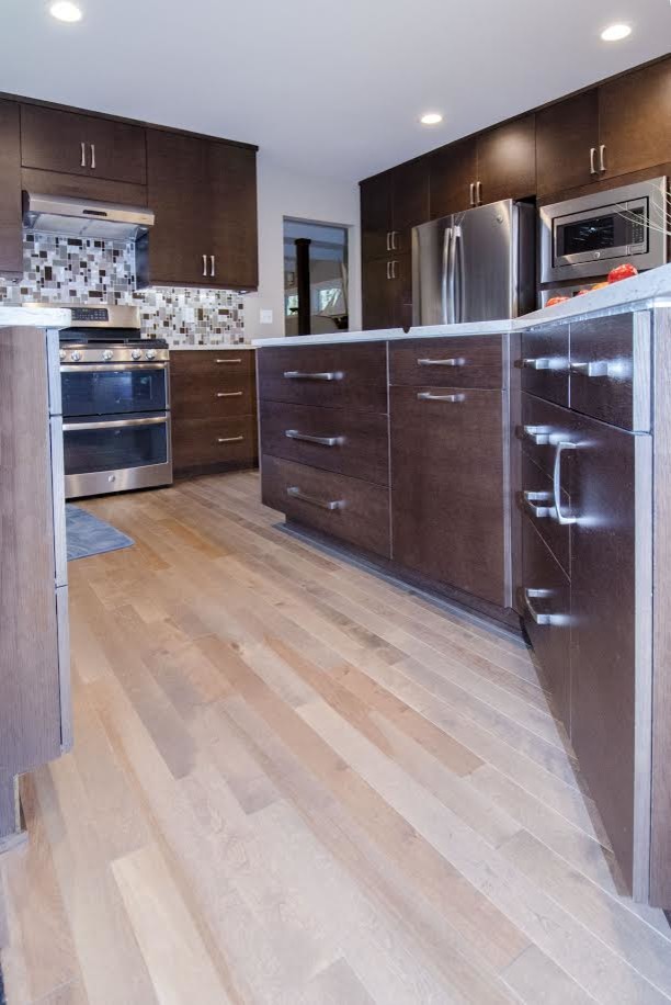 Inspiration for a contemporary l-shaped eat-in kitchen in Seattle with an undermount sink, flat-panel cabinets, brown cabinets, quartz benchtops, grey splashback, glass tile splashback, stainless steel appliances, light hardwood floors, with island and beige floor.