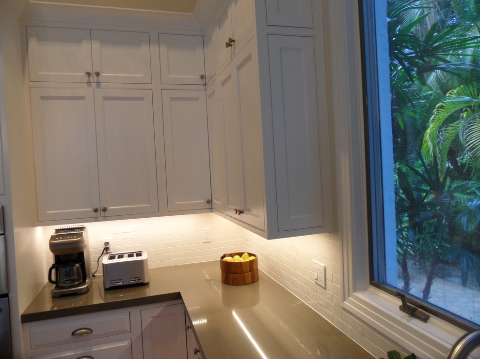 Eat-in kitchen - large transitional l-shaped eat-in kitchen idea in Miami with an undermount sink, shaker cabinets, white cabinets, quartz countertops, white backsplash, ceramic backsplash, stainless steel appliances and an island