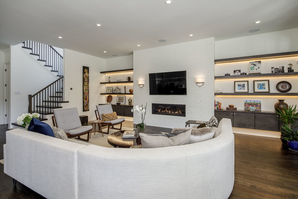 This is an example of a large contemporary open concept living room in Atlanta with white walls, a ribbon fireplace, a brick fireplace surround, a wall-mounted tv, brown floor and dark hardwood floors.