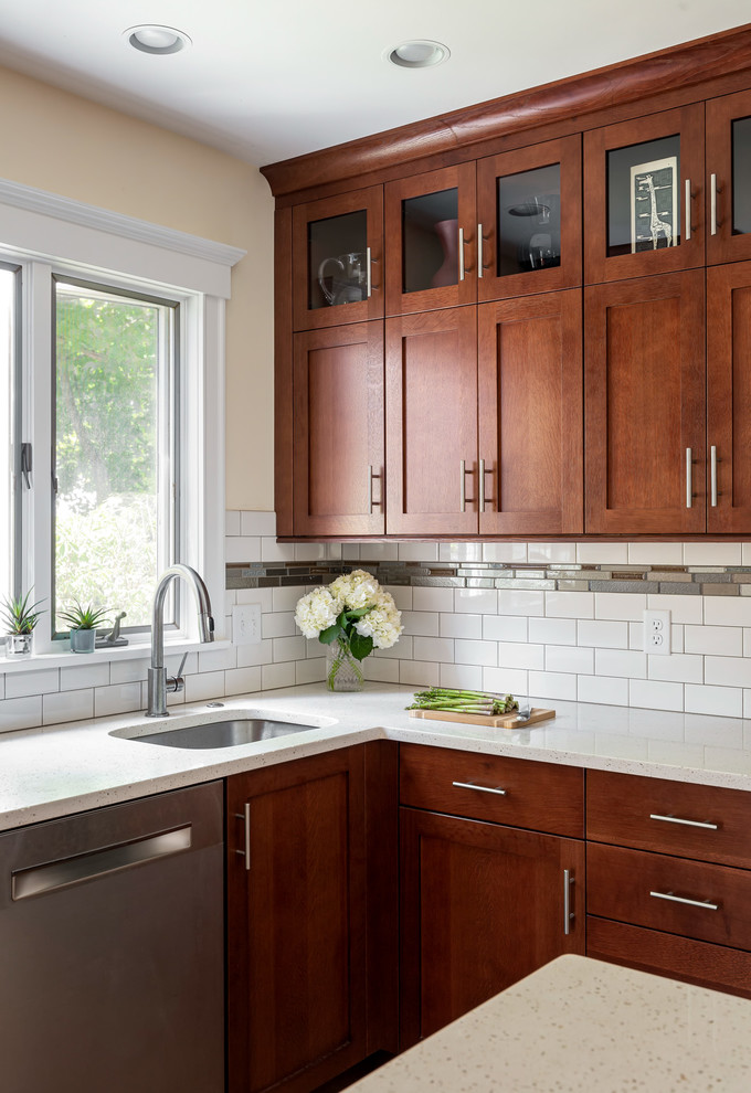 Photo of a mid-sized arts and crafts l-shaped kitchen pantry in Boston with an undermount sink, shaker cabinets, medium wood cabinets, quartz benchtops, white splashback, subway tile splashback, stainless steel appliances, medium hardwood floors, with island, brown floor and white benchtop.