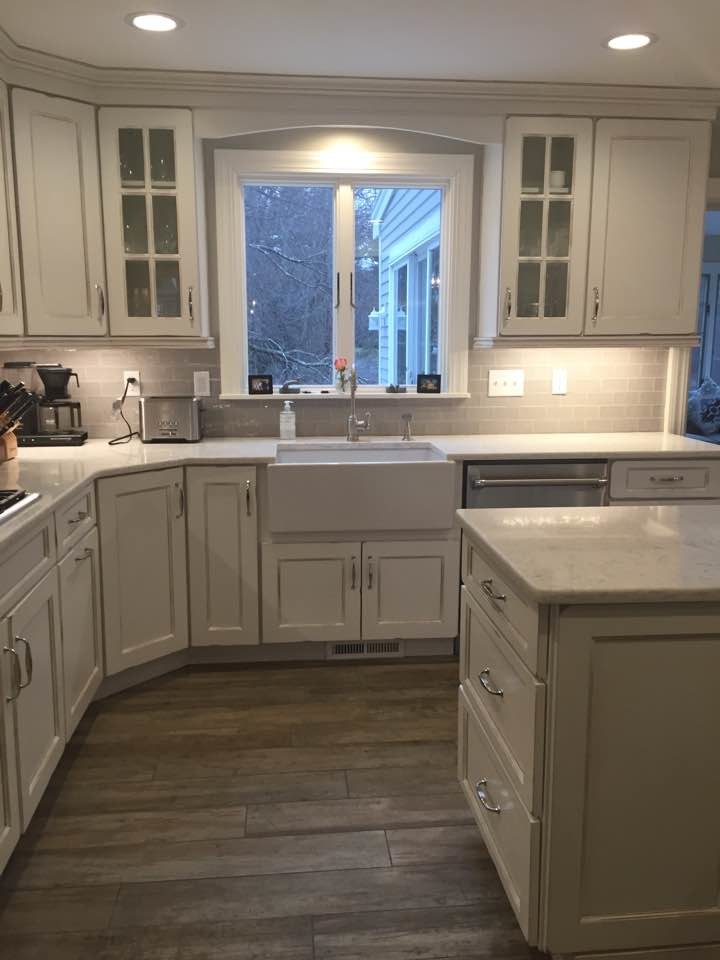 Large country u-shaped open plan kitchen in Boston with a farmhouse sink, recessed-panel cabinets, white cabinets, quartz benchtops, grey splashback, subway tile splashback, stainless steel appliances, porcelain floors and with island.