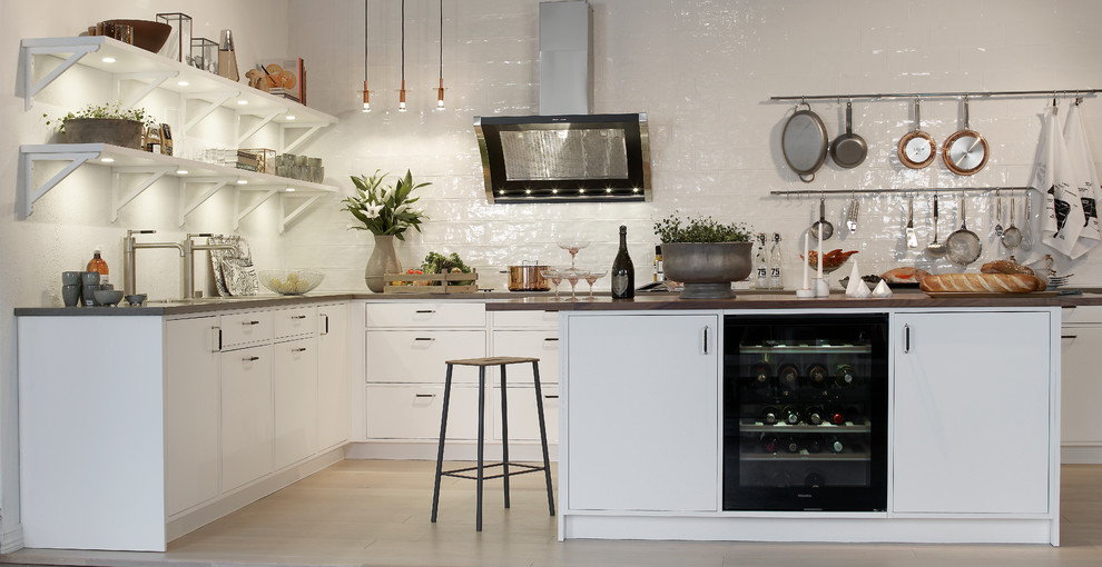 Inspiration for a mid-sized scandinavian single-wall kitchen in Gothenburg with flat-panel cabinets, white cabinets, white splashback, with island, light hardwood floors and wood benchtops.