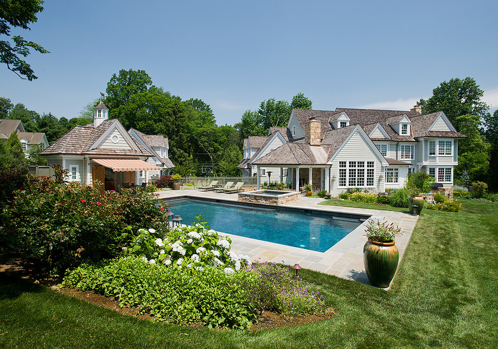 Photo of a mid-sized traditional rectangular pool in Philadelphia with a hot tub and natural stone pavers.