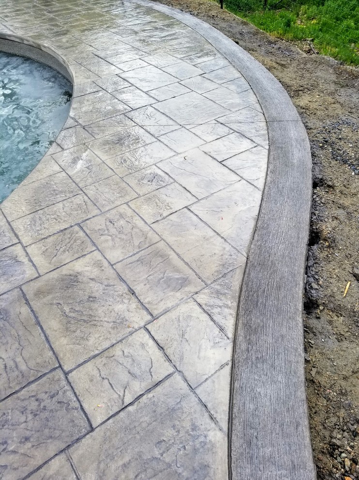 Photo of a large contemporary custom-shaped natural pool in Boston with stamped concrete.