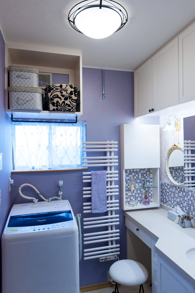 Small traditional single-wall dedicated laundry room with an undermount sink, beaded inset cabinets, beige cabinets, solid surface benchtops, purple walls, vinyl floors, an integrated washer and dryer, white floor and pink benchtop.