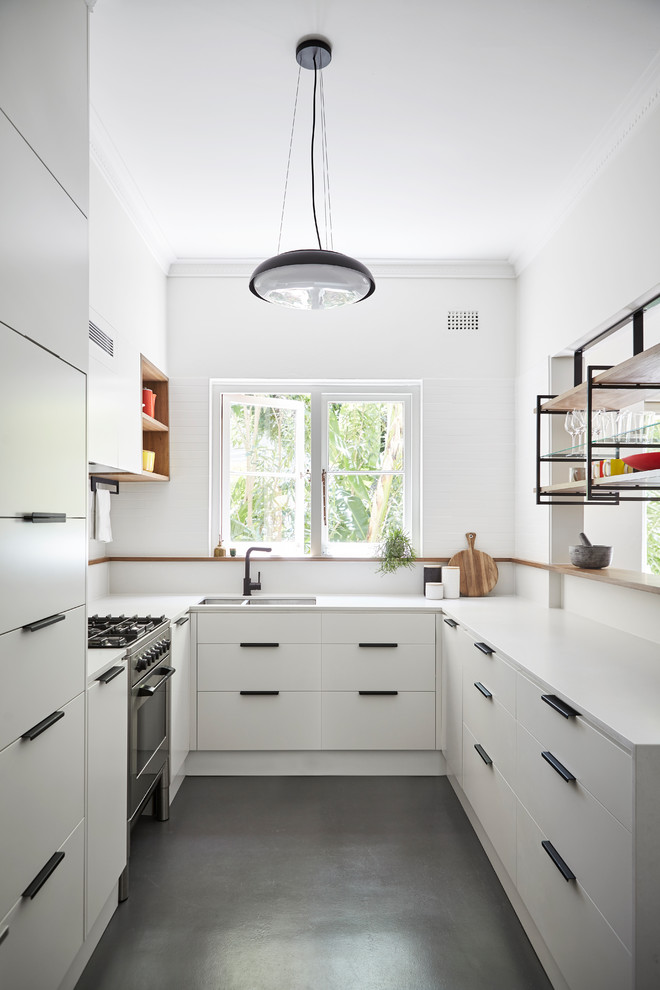 Small contemporary u-shaped kitchen in Sydney with an undermount sink, flat-panel cabinets, white cabinets, quartz benchtops, white splashback, ceramic splashback, concrete floors, a peninsula, grey floor and panelled appliances.