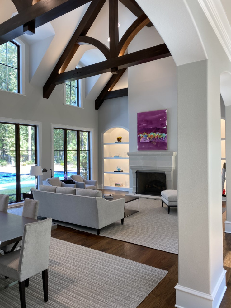 Inspiration for a large transitional open concept living room with grey walls, medium hardwood floors, a stone fireplace surround, exposed beam and brown floor.