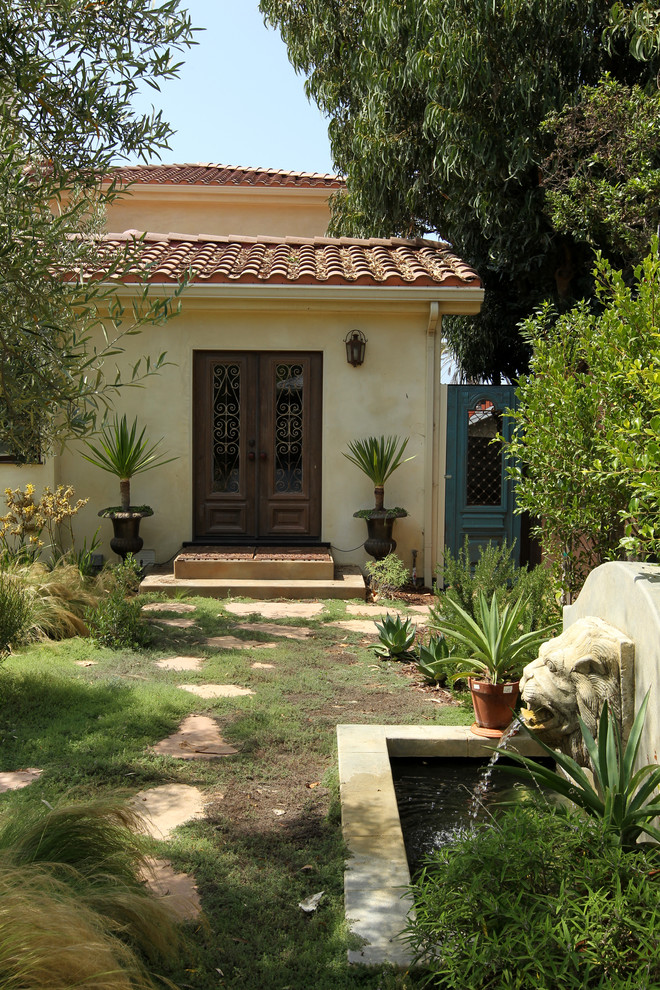 Photo of a large mediterranean backyard full sun xeriscape for summer in Los Angeles with a water feature and natural stone pavers.