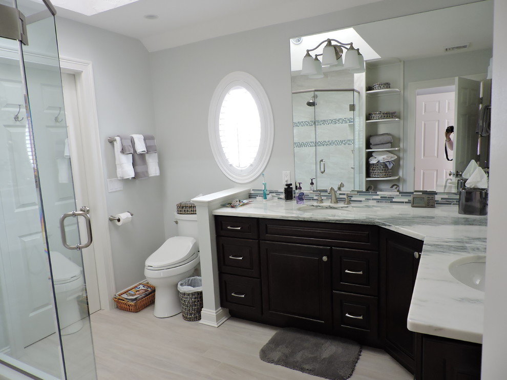 Corner shower - small transitional master gray tile, blue tile, multicolored tile, white tile and matchstick tile porcelain tile and beige floor corner shower idea with gray walls, an undermount sink, marble countertops, a hinged shower door, white countertops, raised-panel cabinets, black cabinets and a two-piece toilet