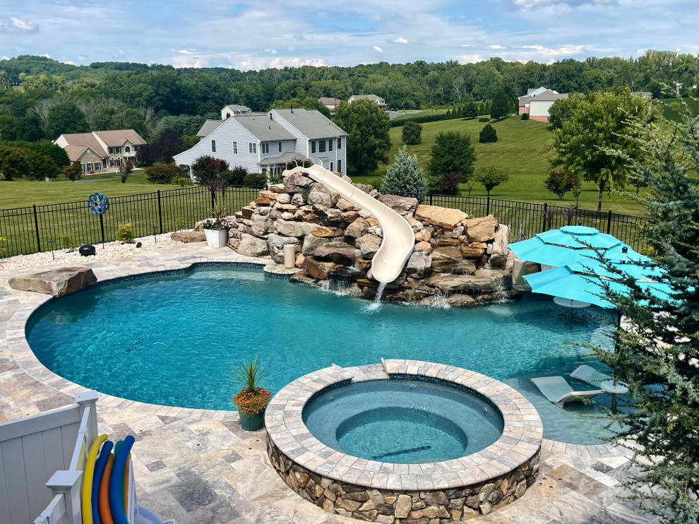 Idee per una grande piscina naturale moderna personalizzata dietro casa con un acquascivolo e pedane