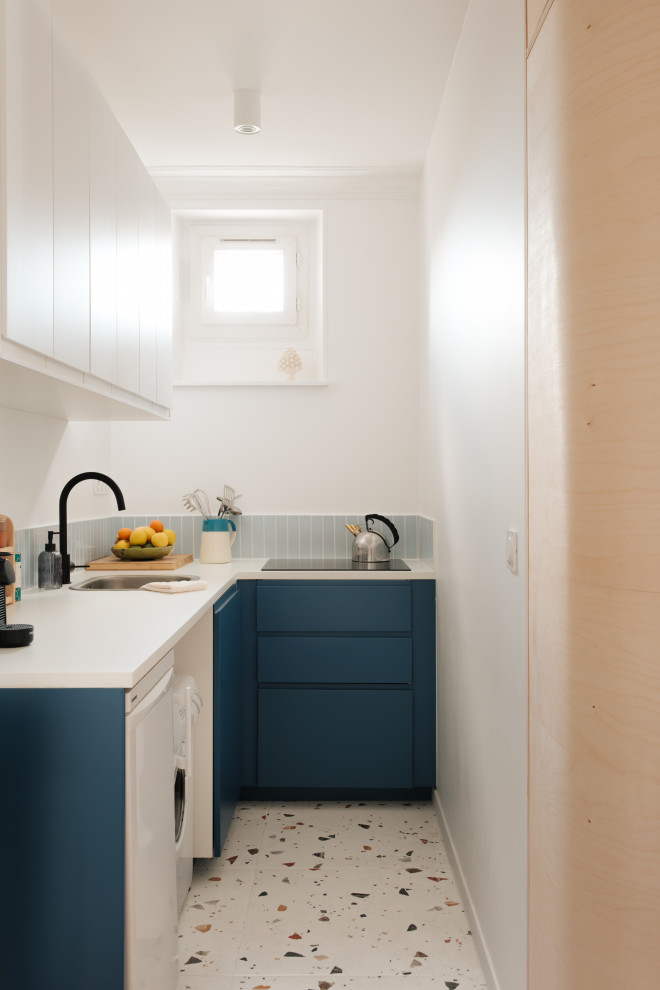 Idée de décoration pour cuisine ouverte in L With un évier 1 bac, un placard à porte affleurante, des portes de placard bleues, un plan de travail en stratifié, une crédence bleue, une crédence en carreau briquette, un sol en terrazzo, un sol blanc and un plan de travail blanc.