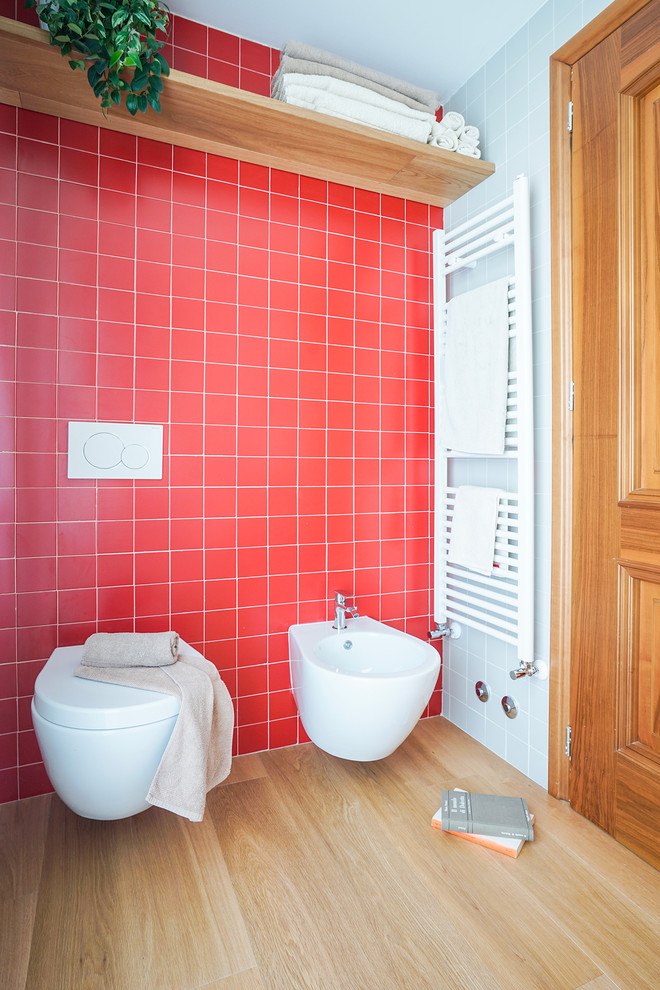 Photo of a small contemporary 3/4 bathroom in Florence with a wall-mount toilet, red tile, red walls, light hardwood floors, beige floor and ceramic tile.