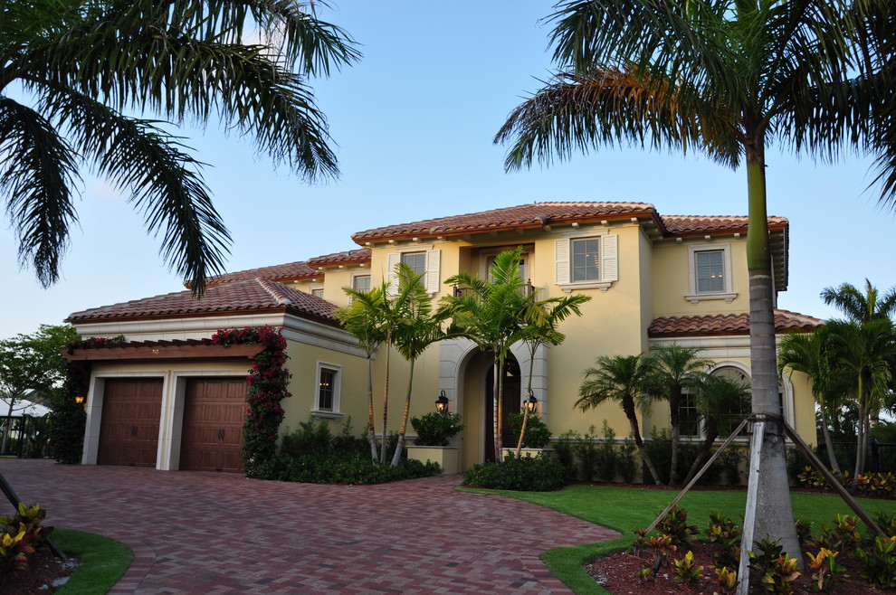 This is an example of a large mediterranean two-storey stucco yellow exterior in Miami.