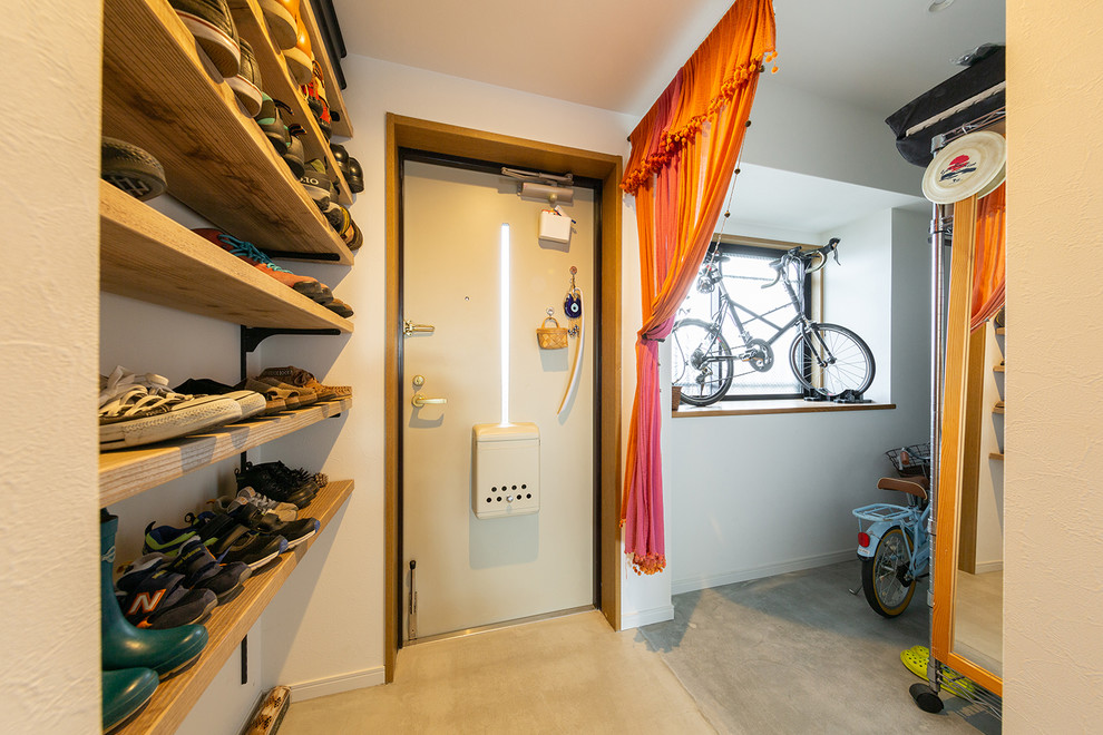 他の地域にあるアジアンスタイルのおしゃれな玄関ホール (白い壁、コンクリートの床) の写真