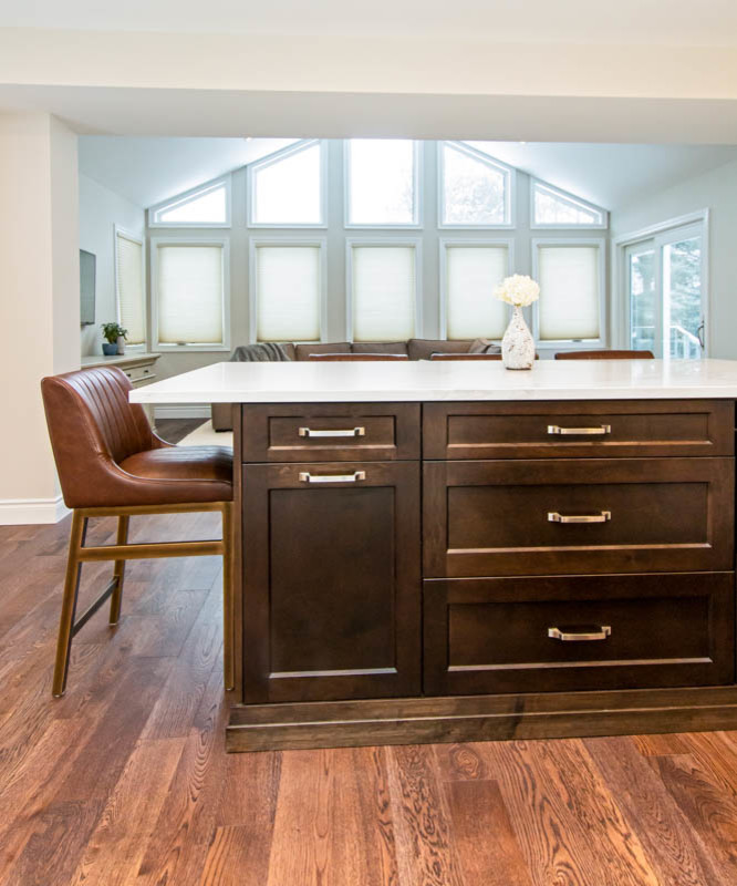 Example of a mid-sized transitional l-shaped medium tone wood floor and brown floor open concept kitchen design with an undermount sink, shaker cabinets, white cabinets, quartzite countertops, white backsplash, stone tile backsplash, stainless steel appliances, an island and white countertops
